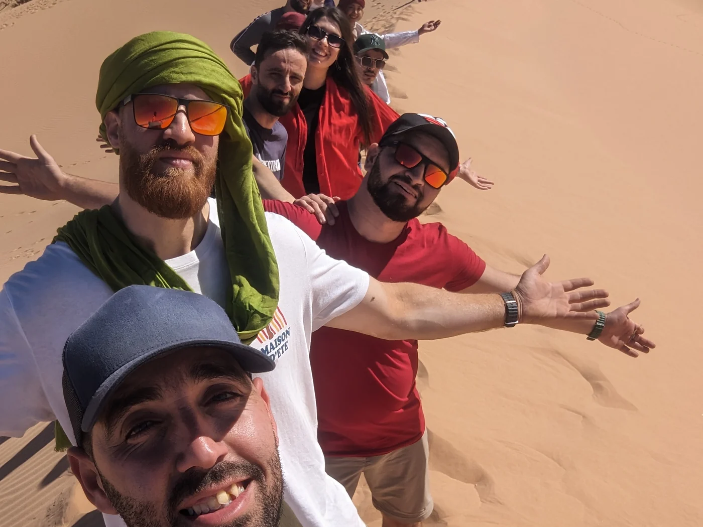 Podróżni Tourago na wydmie w El Bayadh, z rozłożonymi rękami